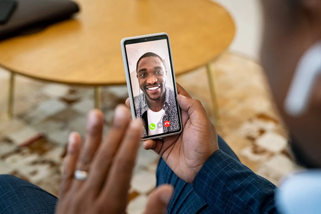 Close up of young african man on video call with boss using smartphone.